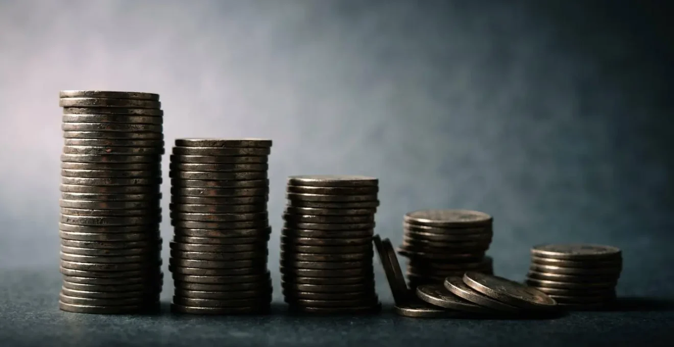 Pièces de monnaie empilées avec effet de dégradé suggérant l'érosion progressive